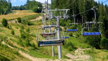 Güneşli yaz günlerinde kulübelerin çalıştığı yüksek uzun bir teleferik hattı. Yaz aylarında dağda seyahat ve turizm kavramı