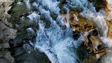 Manzara hızlı ve tehlikeli dağ nehri ve şelale kayalıklara ve kayalara düşüyor.
