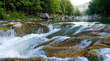 Dağlardaki nehirde çağlayan kayaların ve şelalelerin güzel manzarası
