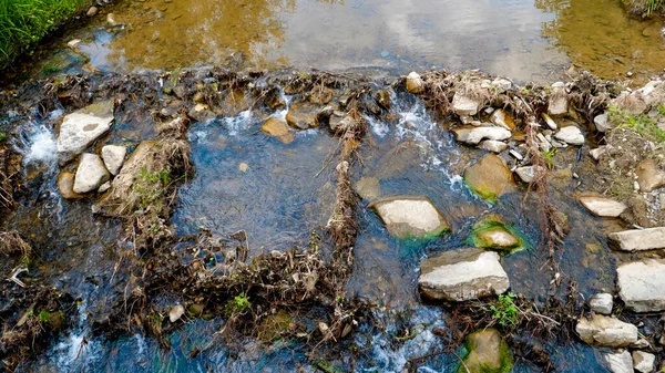 Vista dall'alto del fiume di montagna sporco e inquinato. Il concetto di disastro ecologico. detriti e rifiuti di plastica sdraiati sulle rocce al fiume. — Foto Stock