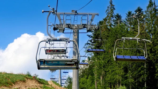 Ski lift and cable cars working on mountain ski resort at sunny summer day. Concept of travel and tourism in mountain at summer