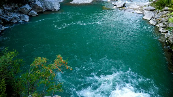 Горная река, текущая в красивом озере с чистой изумрудной водой в горах — стоковое фото