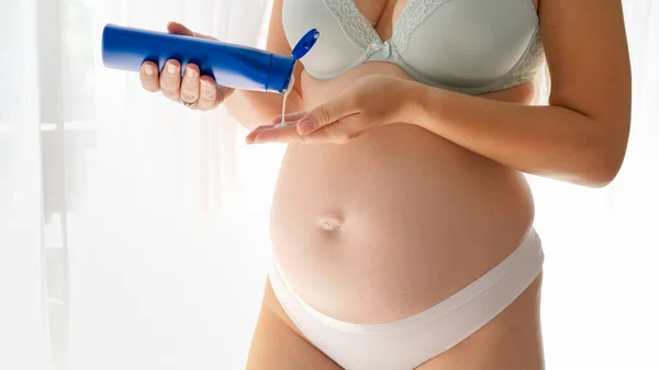 保湿化粧水やアリのストレッチマーククリームを適用ランジェリーで妊婦の閉鎖は、腹と体を漕ぎにクリームをマークします。美しさ、妊娠と医療の概念. — ストック写真