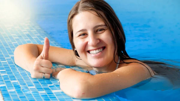 Retrato de mujer alegre feliz sonriente relajándose en la piscina y mostrando los pulgares hacia arriba. Gente feliz de vacaciones o vacaciones —  Fotos de Stock