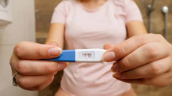 Primer plano de la mujer con la prueba de embarazo positiva y mostrándola en la cámara. —  Fotos de Stock