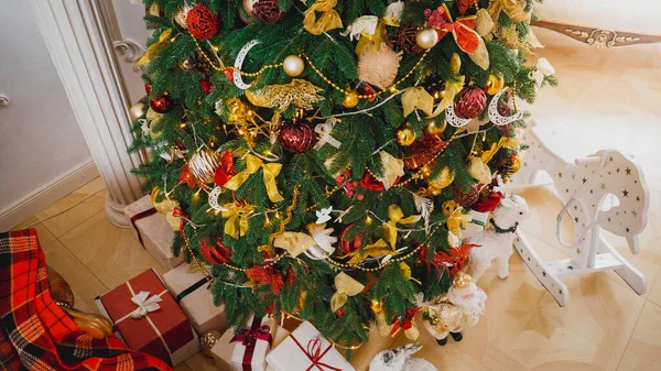 Uitzicht vanaf de top van versierde kerstboom, houten speelgoed en cadeautjes op de vloer in de woonkamer — Stockfoto