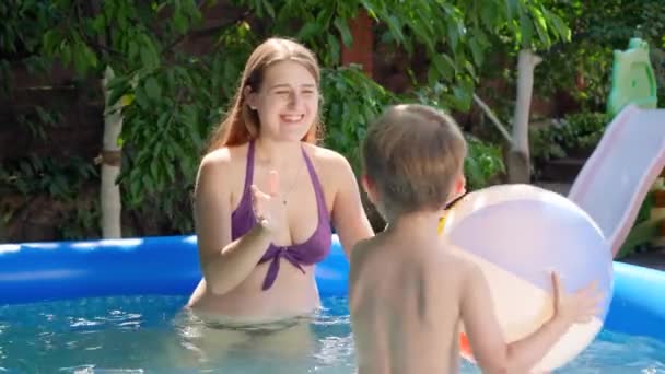 Leuke kleine jongen spelen in opblaasbaar zwembad met kleurrijke strandbal. Familie vakantie en vakantie — Stockvideo