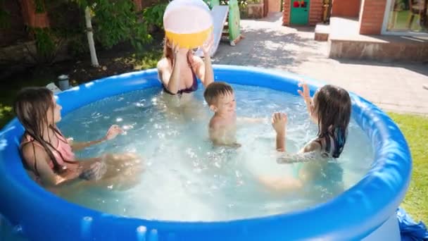 Feliz rindo crianças com a mãe se divertindo e brincando com bola inflável no quintal de natação. Família férias de verão e feriados — Vídeo de Stock
