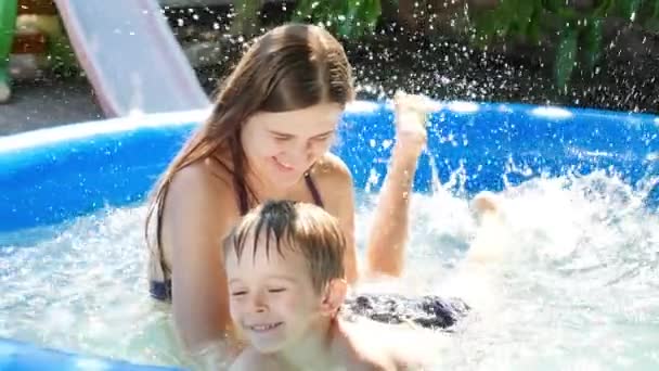 Zeitlupe eines glücklichen kleinen Jungen und einer jungen Mutter, die im aufblasbaren Außenpool schwimmen und planschen. Familie mit Kindern Sommerurlaub und Urlaub — Stockvideo