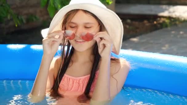 Linda menina adolescente msiling relaxando na piscina e tirar óculos de sol. Férias de verão e férias — Vídeo de Stock