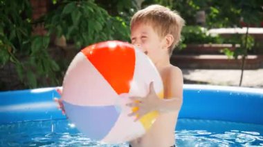 Açık havuzda şişme plaj topuyla oynayan 5 yaşındaki sevimli bir çocuğun portresi. Mutlu ve neşeli yaz tatili ve tatil kavramı