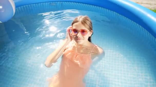 노천 수영장에 누워서 편안하게 쉬고 있는 행복 한 미소짓는 소녀의 사진이 위에 있다. 행복하고 즐거운 여름 휴가와 휴가에 대한 개념 — 비디오