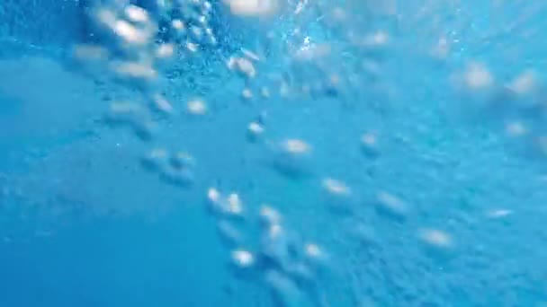 Langzame beweging van de waterstroom en zwevende luchtbellen in het heldere blauwe water. Mooi onder water achtergrond of achtergrond — Stockvideo