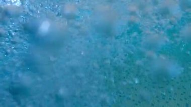 Yavaşça çekilen hava kabarcıkları yüzme havuzunun berrak mavi sularında yavaşça yüzüyor.