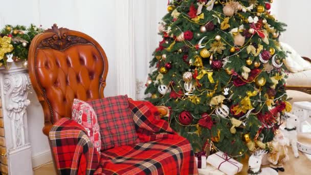 Hermosa sala de estar con sillón y chimenea decorada para celebrar la Navidad y el Año Nuevo. Fondo o telón de fondo de vacaciones de invierno. — Vídeo de stock