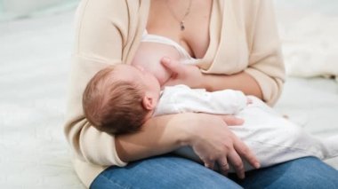 Yatakta oturup bebeğini anne sütüyle besleyen güzel bir annenin görüntüsü. Sağlıklı ve doğal bebek emzirme kavramı.