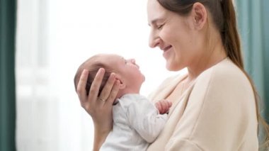 İki haftalık erkek bebek portresi. Genç ve şefkatli bir annesi var. Evdeki büyük pencerenin önünde. Aile mutluluğu ve küçük çocuklu sevgi dolu ebeveynler.