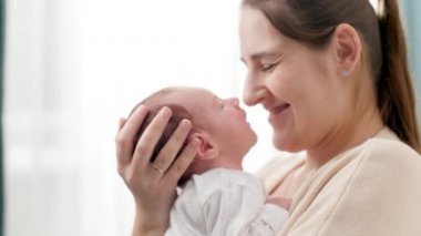 Küçük sevimli bir bebeğin ve gülümseyen bir annenin birbirine büyük bir pencereden baktığı yakın plan portresi. Aile mutluluğu ve küçük çocuklu sevgi dolu ebeveynler.