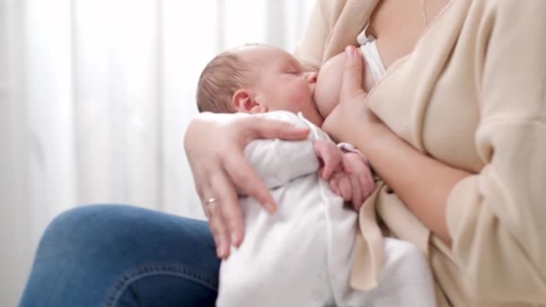 Joven madre cuidadora sentada en la cama y alimentando a su bebé recién nacido con leche materna. Concepto de nutrición saludable y natural de la lactancia materna del bebé. — Vídeo de stock