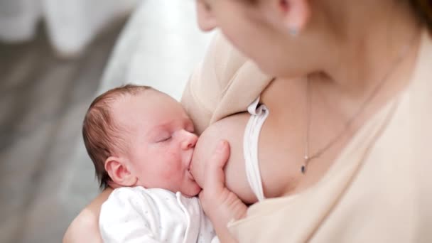 Utsikt ovanifrån över unga mor ser och gunga hennes nyfödda barn suger mjölk från bröstet. Begreppet friska och naturliga baby amning näring. — Stockvideo