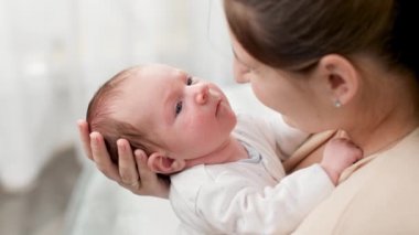 Genç ve şefkatli annenin kucaklaşması ve büyük pencereli yeni doğmuş bebeğe sarılmasına yukarıdan bakınca. Aile mutluluğu ve küçük çocuklu sevgi dolu ebeveynler.