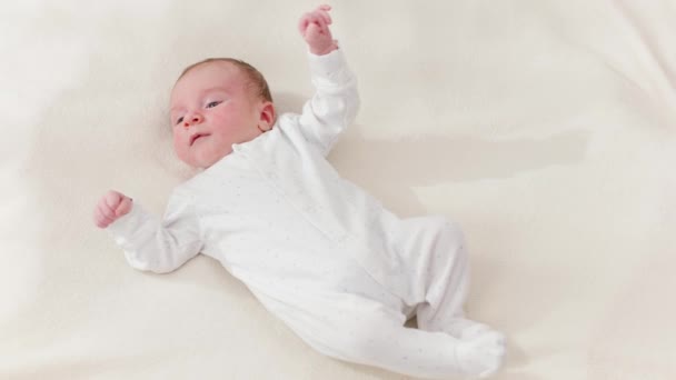 Schwenkbild des niedlichen Neugeborenen, das im warmen Sonnenlicht auf dem Bett liegt — Stockvideo