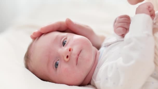 Nahaufnahme einer glücklich lächelnden Mutter und eines entzückenden neugeborenen Jungen lyin im Kinderbett vor einem großen Fenster. Konzept des Familienglücks und liebevoller Eltern mit kleinen Kindern — Stockvideo