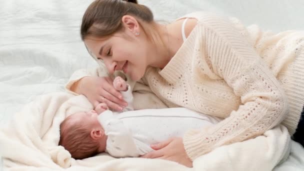 Draufsicht der schönen lächelnden Mutter, die neben ihrem Neugeborenen liegt und auf ihren Sohn schaut. Konzept des Familienglücks und liebevoller Eltern mit kleinen Kindern — Stockvideo