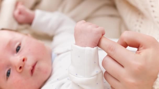 Closeup of newborn baby boy holding and catching mothers finger with little hands. Concept of family happiness and loving parents with little children — Stock Video