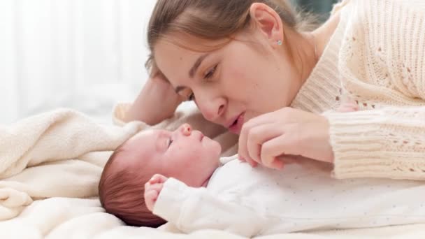 Portret szczęśliwej uśmiechniętej i śmiejącej się młodej matki łaskoczącej i bawiącej się z małym synkiem w łóżku. Pojęcie szczęścia rodzinnego i kochających rodziców z małymi dziećmi — Wideo stockowe