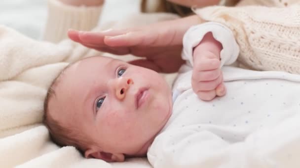 Primo piano di adorabile neonato sdraiato nella culla. Giovane altra accarezzando il suo bambino con mano. Concetto di felicità familiare e genitori amorevoli con bambini piccoli — Video Stock