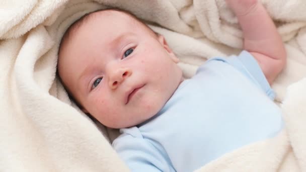 Nahaufnahme eines kleinen 1 Monate alten Jungen, der in einem großen weichen Kinderbett liegt und sich mit den Händen bewegt — Stockvideo