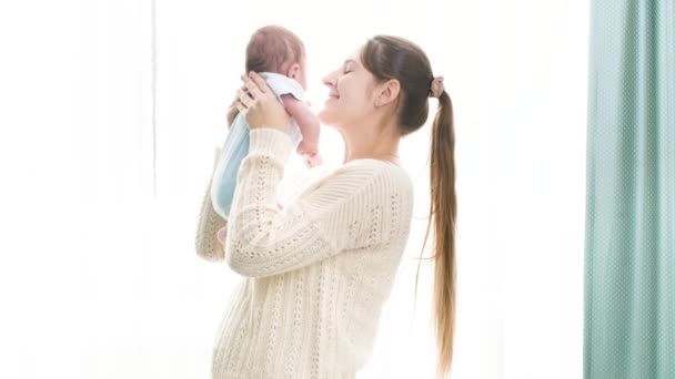 Felice donna sorridente con un piccolo bambino di 1 mese che abbraccia e abbraccia il grande vento in camera da letto. Concetto di felicità familiare e genitori amorevoli con bambini piccoli — Video Stock