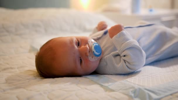 Retrato del bebé recién nacido acostado en la cama por la noche y chupando chupete o chupete. Concepto de recién nacidos, padres cariñosos y cariñosos y felicidad familiar — Vídeos de Stock