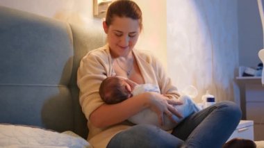 Güzel gülümseyen anne yeni doğmuş bebeğine meme veriyor. Anne ve babası geceleri çocuğu yatakta besliyor. Sağlıklı ve doğal bebek beslenmesi kavramı. Anne ve çocuğun sağlığı