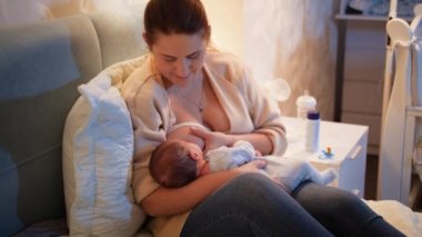 Genç msiling kadın yatakta uzanıyor yeni doğmuş bebeğini emziriyor karanlık yatak odasında anne sütüyle sağlıklı ve doğal bebek beslenmesi kavramı. Anne ve çocuğun sağlığı