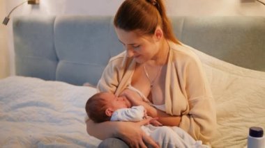 Güzel gülümseyen anne yeni doğmuş bebeğini sallıyor süt yiyor ve meme emiyor. Sağlıklı ve doğal bebek beslenmesi kavramı. Anne ve çocuğun sağlığı