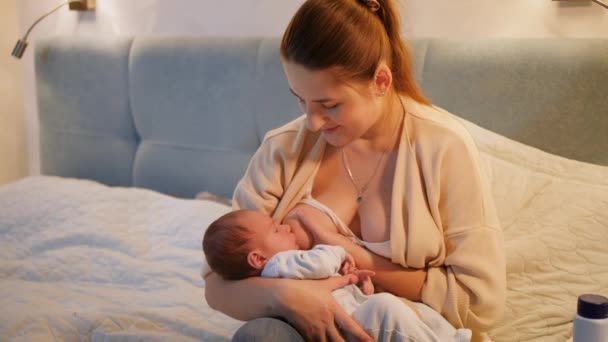 Bella madre sorridente guardando e cullando il suo bambino appena nato mangiare latte e succhiare il seno. Concetto di nutrizione sana e naturale del bambino. Salute della madre e del bambino — Video Stock