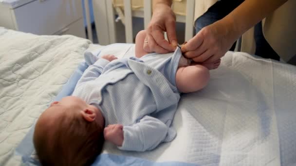 Primo piano della madre che cambia i pannolini e veste il suo piccolo figlio sul letto di notte. — Video Stock