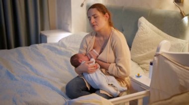 Yorgun ve bitkin bir anne, yeni doğmuş bebeğini gece yatağında sütle beslerken uykuya dalıyor. Sağlıklı ve doğal bebek beslenmesi kavramı. Anne ve çocuğun sağlığı.