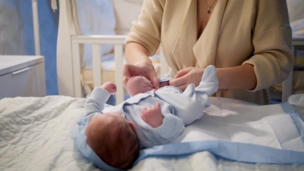 Primer plano de la mujer joven vistiendo a su bebé recién nacido con ropa limpia y seca. Noches sin dormir y cuidado de los padres. — Vídeos de Stock