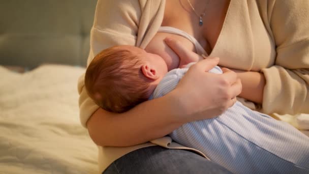 Lindo bebé recién nacido chupando leche de madres sentadas en el pecho por la noche. Concepto de nutrición saludable y natural del bebé. Salud de la madre y del niño. — Vídeos de Stock