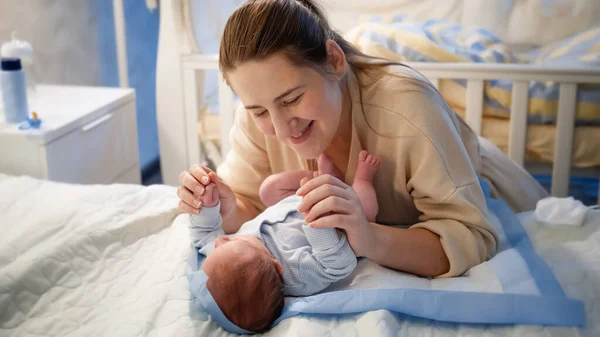 Güzel bir annenin portresi. Küçük bebeğinin elini tutuyor. Geceleri yatağa uzanıyor. — Stok fotoğraf