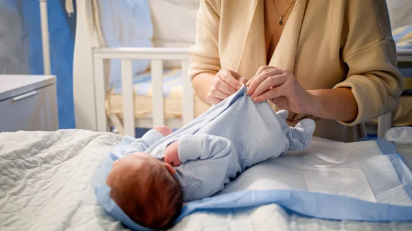 Primer plano de la mujer joven vistiendo a su bebé recién nacido con ropa limpia y seca. Noches sin dormir y cuidado de los padres. — Foto de Stock