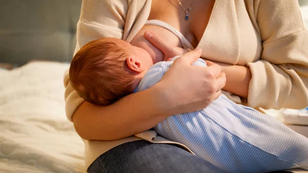 Lindo bebé recién nacido chupando leche de madres sentadas en el pecho por la noche. Concepto de nutrición saludable y natural del bebé. Salud de la madre y del niño. — Foto de Stock