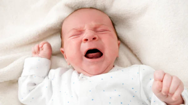 Closeup portrait of newborn baby crying and screaming while lying in crib — Stock Photo, Image