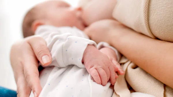 Primer plano de los bebés recién nacidos con las manos sobre la madre mientras chupa el pecho y come leche. Concepto de nutrición saludable y natural de la lactancia materna del bebé. — Foto de Stock