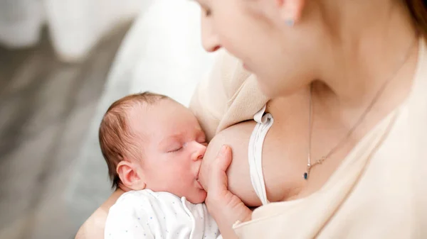 Widok z góry na młodą matkę patrzącą i kołyszącą swoje nowonarodzone dziecko ssące mleko z piersi. Pojęcie zdrowego i naturalnego żywienia piersią dla niemowląt. — Zdjęcie stockowe