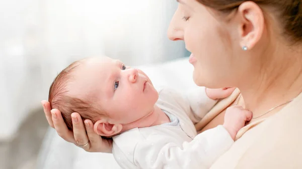 Oben Blick auf junge fürsorgliche Mutter, die ihr neugeborenes Kind im Schlafzimmer mit großem Fenster umarmt und kuschelt. Konzept des Familienglücks und liebevoller Eltern mit kleinen Kindern — Stockfoto