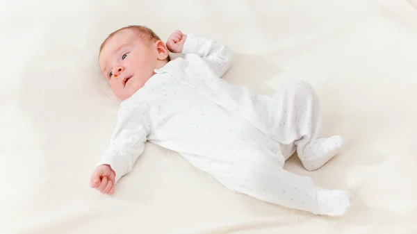 View from above on adorable 1 months old baby boy lying on white blanket on bright sunny day. — Stock Photo, Image